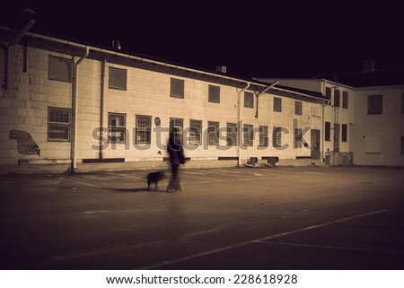 Man walking black dog in depressing industrial area