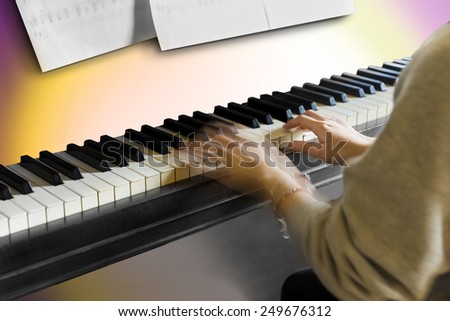Hands of young woman playing the piano. Blurred motion.