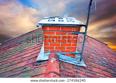 Close up of chimney on tiled roof with fungus on old worn roof tiles