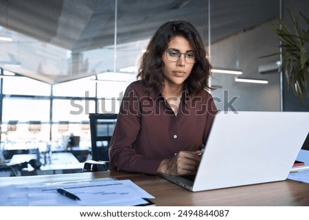 Serious female surfing laptop near modern building