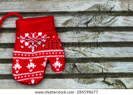 Christmas Red Knitted Mitten with Snowflake Motives on wooden background