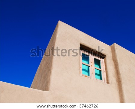 Window in a Southwest stucco building with a turquoise tint in contrast to a deep blue sky