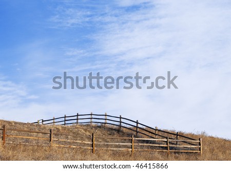 Simple fenced corner of a pasture on the top of a hill with view of big open sky and clouds on the Colorado prairie