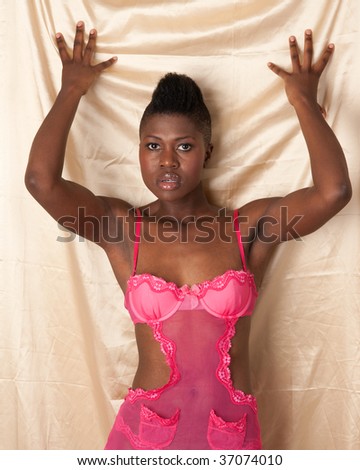 Beautiful african american woman in pink lingerie on gold sheet