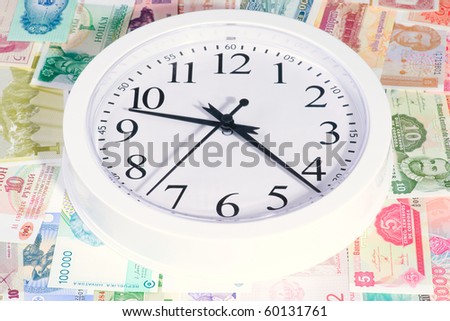 White clock laying on the world currency bank notes