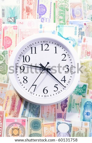 White clock laying on the world currency bank notes
