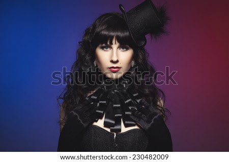 Beautiful fantasy gothic vampire brunette woman in sexy black satin corset, burlesque hat, jabot and long gloves
