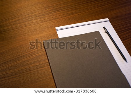 Pad of paper, file & pencil on wooden business desk