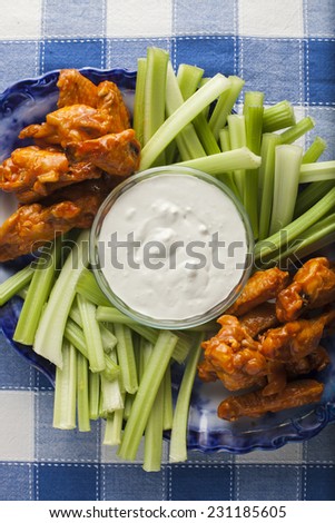 Buffalo wings with blue cheese dressing and celery sticks.
