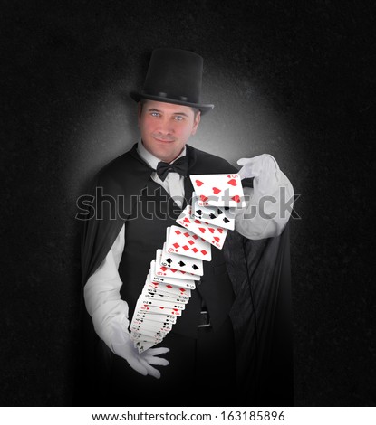 A magician has playing cards floating in the air on a black background for an entertainment or illusion concept.
