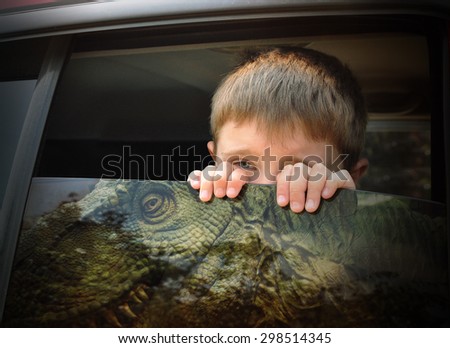 A young scared child is looking out the car window at a dangerous t-rex dinosaur for an imagination, history or travel concept.