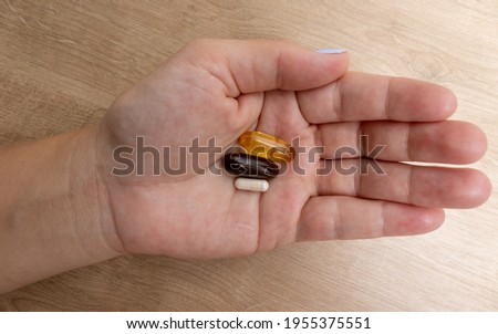 A white woman's hand holding a combination of medicine and vitamins in yellow, black and white over her left hand. Referring to food, medicine and health choices. ストックフォト © 