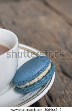 Blue vanilla flavored macaron beside the coffee cup on the plate