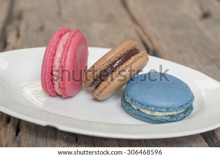 Three colorful macaron - Blue macaron vanilla flavor, pink macaron strawberry flavor and brown macaron chocolate flavor on the plate