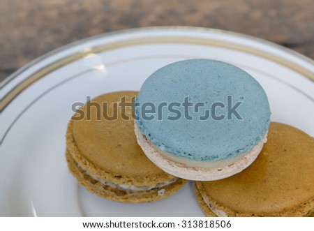 Three macarons stacked on the plate , blue vanilla flavored macaron on top , close up view.