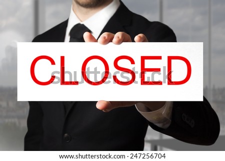 businessman in black suit holding sign closed