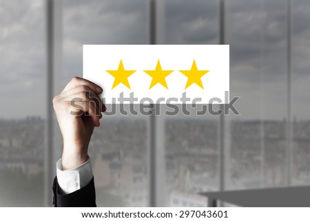 businessmans hand holding up small sign three rating stars