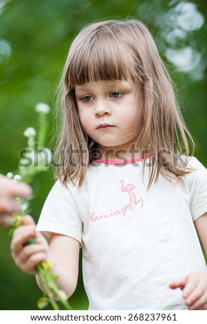 Girl picking flowers. Beautiful little girl picks flowers on a spring green meadow. Shallow depth of field