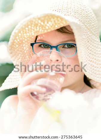Girl drinking water. Summer little girl in straw hat outdoor portrait. Happy childhood. Vintage Sunny portrait of adorable little girl.