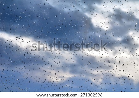 Wet window with rain drops and cloudy stormy sky background