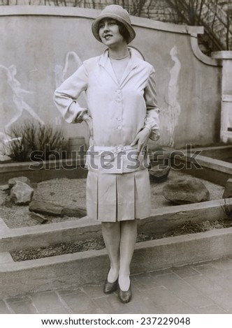 1927 suit with a mid-knee pleated skirt and matching waistless hip-belted jacket The outfit is toped by a cloche hat. March 1927.