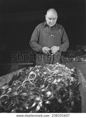 Conversion, copper and brass processing, gaging copper rotating bands, man checking the diameter of bands, Chase Copper and Brass Company, Euclid, Ohio, photograph by Alfred T. Palmer, February, 1942
