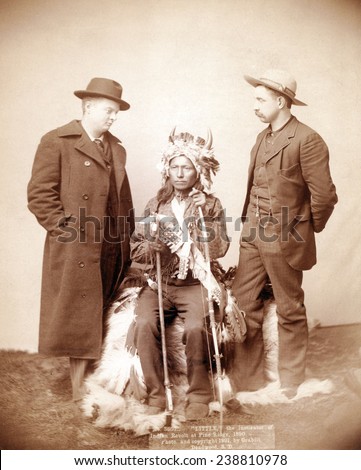 Little, Oglala band leader, full-length studio portrait seated between two men who are standing on either side of him, photograph by John C. H. Grabill, 1891