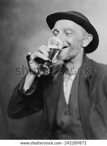Happy old man drinking glass of beer, with his daintier finger extended. 1937.