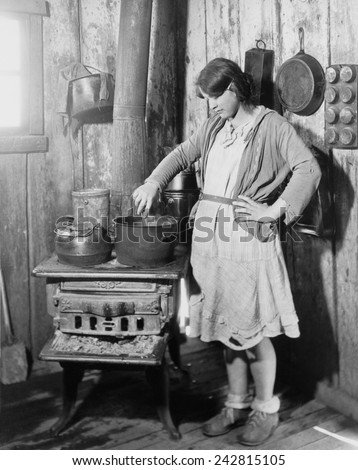 The teenage daughter of a an impoverished Arkansas farmer cooking on an old stove while her mother was in a tuberculosis sanitarium during the Great Depression. Red Cross photo from ca. 1930.