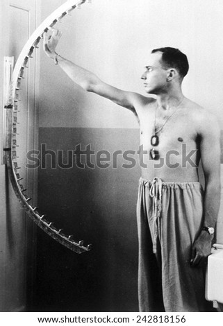 Physical therapy patient using finger walker to increase flexibility and range of motion in shoulder. Ca. 1950.