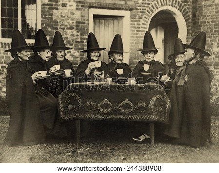 Eight women in high hats having tea. They are not a group of witches but the members of the Holy and Undivided Trinity of Castle Rising, Norfolk, England. Ca. 1920.