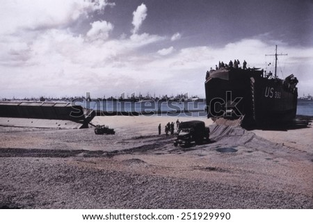 Trucks exit from the hold of a U.S. LST (Landing Ship Tank) on a Normandy beach in June 1944.