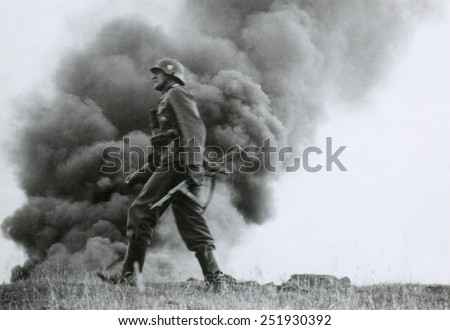 German officer of assault troops during the Nazi invasion of the Soviet Union, (Russia) In the Summer of 1941, the soldier strides against a background of burning buildings, during World War 2.