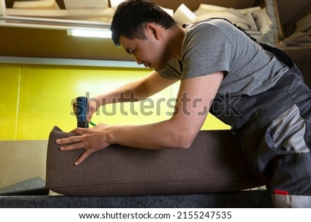 Furniture upholstery. A carpenter fixes the fabric with a pneumatic stapler. Foto stock © 