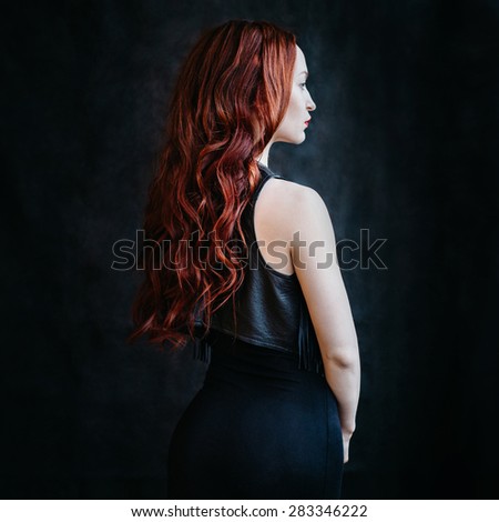 The girl\'s portrait with red long hair and red lips against a dark background