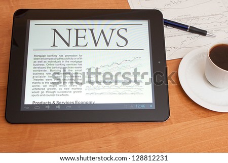 Tablet PC shows latest news on screen, which lying on work place.
