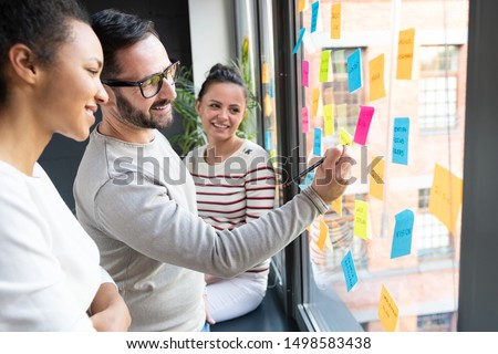 Business people meeting at office and use post it notes to share idea. Brainstorming concept. Sticky note on glass wall.