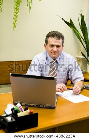Smiling Businessman seated at desk in office setting
