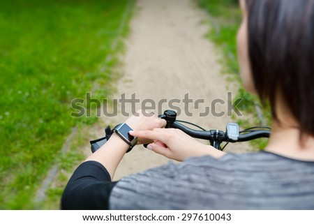Woman riding a bike with a smartwatch heart rate monitor. Smart watch concept.