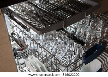 Open dishwasher with clean utensils in it.