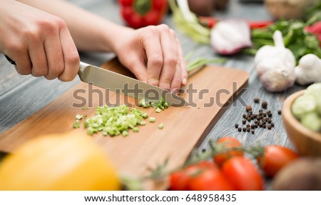 Chef cuts the vegetables into a meal. Preparing dishes. A woman uses a knife and cooks. 商業照片 © 