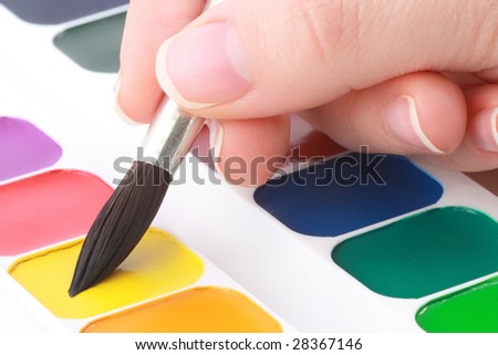 Painter taking yellow water-colour paint by paintbrush.