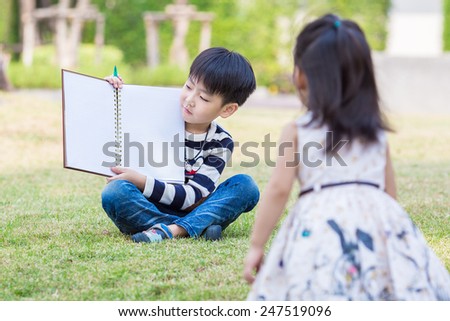 asian brother and sister with the book in the garden
