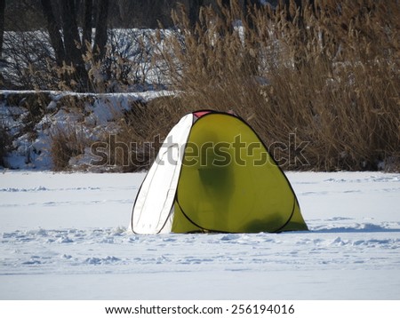 Fishing tent in the snow in winter sunny day.