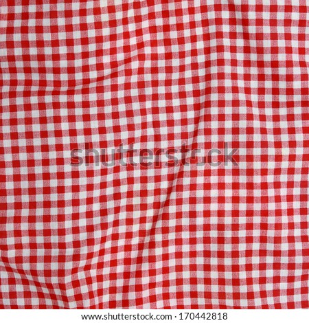 Abstract background texture of a red and white checkered picnic blanket. Red linen crumpled tablecloth.