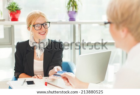 Beautiful female worker issuing credit card to a customer
