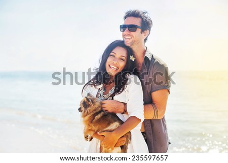 couple holding a puppy on a beach