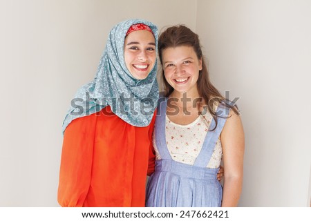friendship of the religions concept: muslim and christian girl together