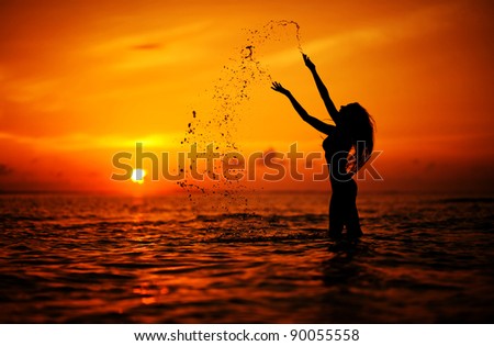 Long hair woman silhouette in the sea splashing water