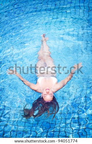 Young woman in swimsuit, swimming in pool, top view